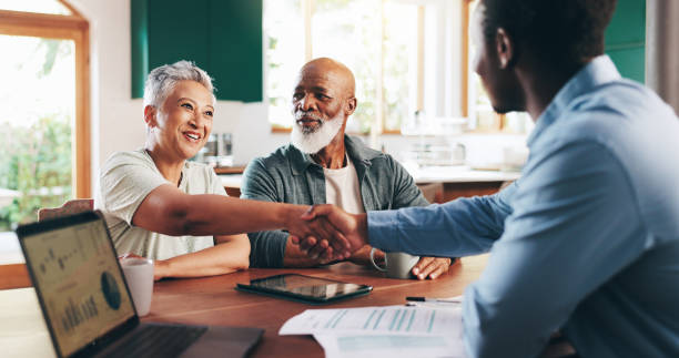 Senior couple shaking hands with an advisor at a table